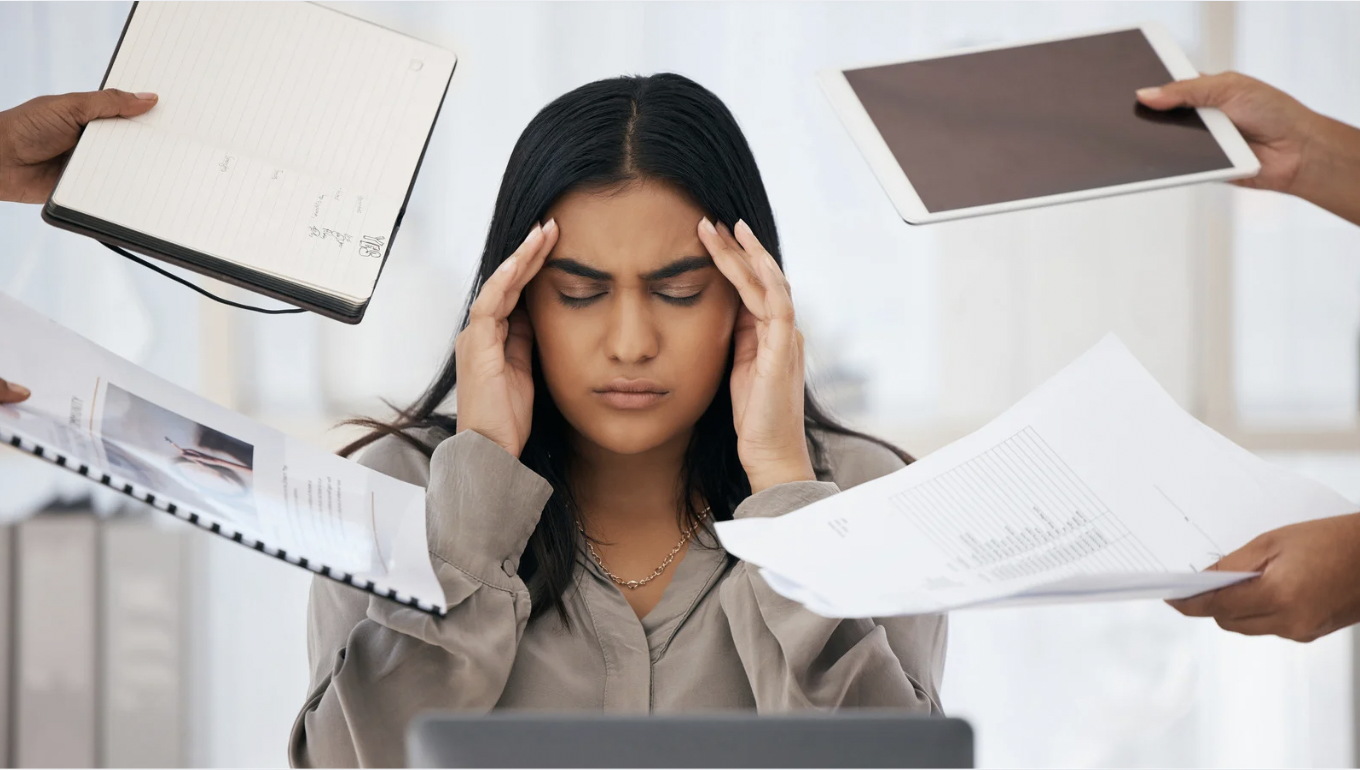 Profesional con las manos en la cabeza ante una situación de sobrecarga de trabajo y estrés laboral.
