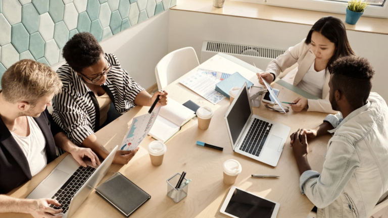Equipo de profesionales reunidos alrededor de una mesa, revisando documentos y colaborando en un entorno de trabajo.