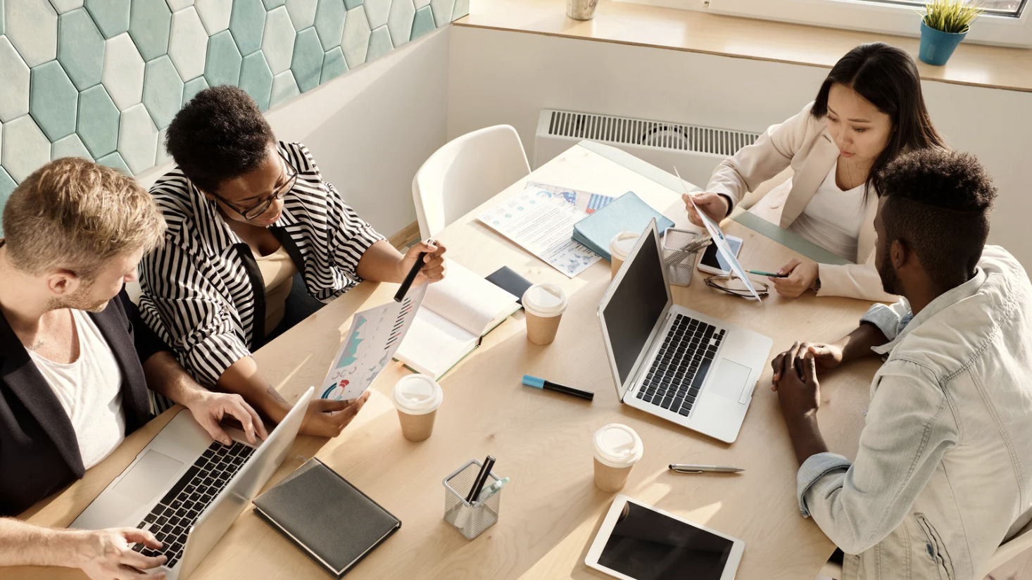 Equipo de profesionales reunidos alrededor de una mesa, revisando documentos y colaborando en un entorno de trabajo.
